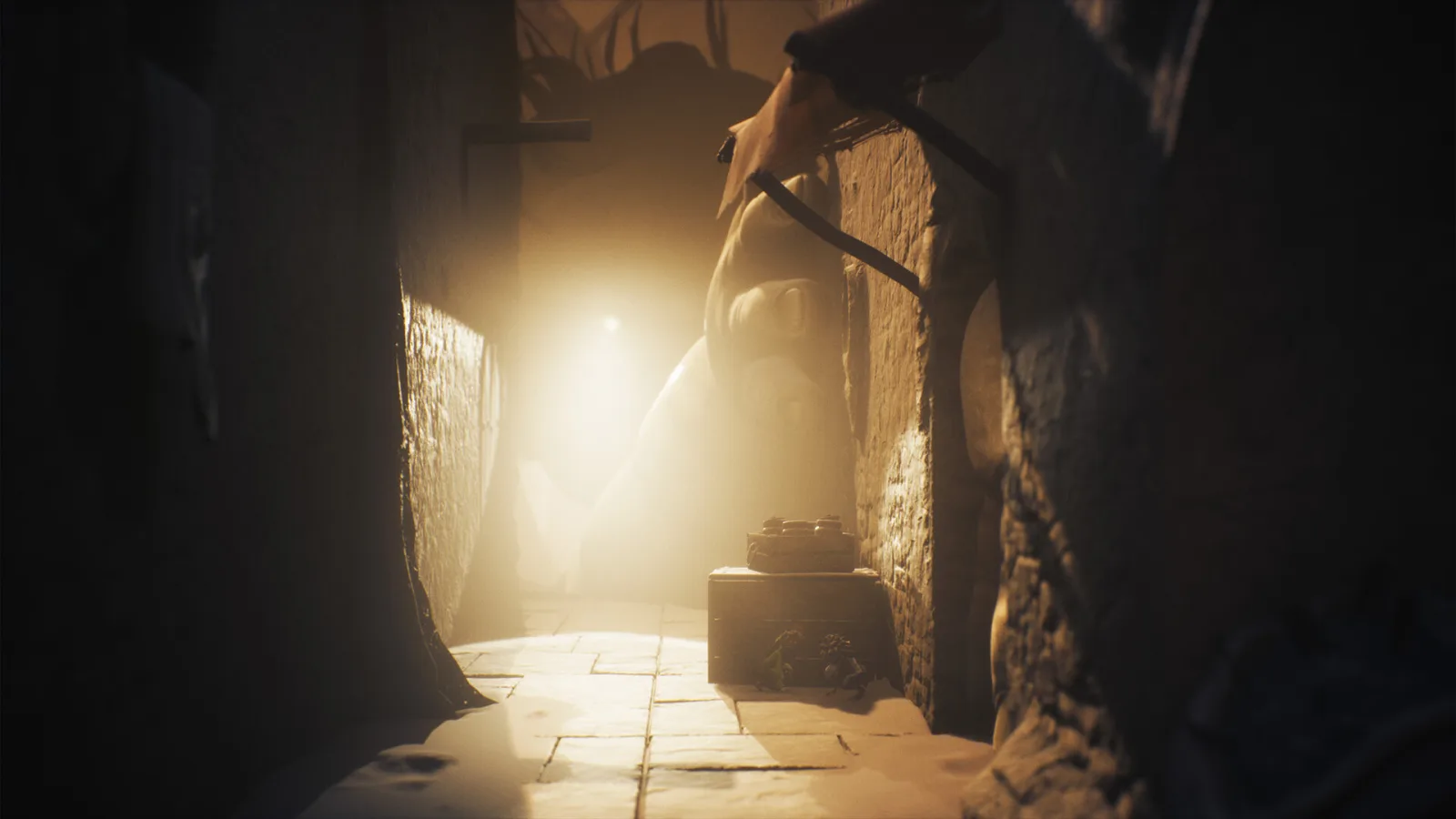 Little Nightmares III: a massive silhouette looms at the end of a lit corridor