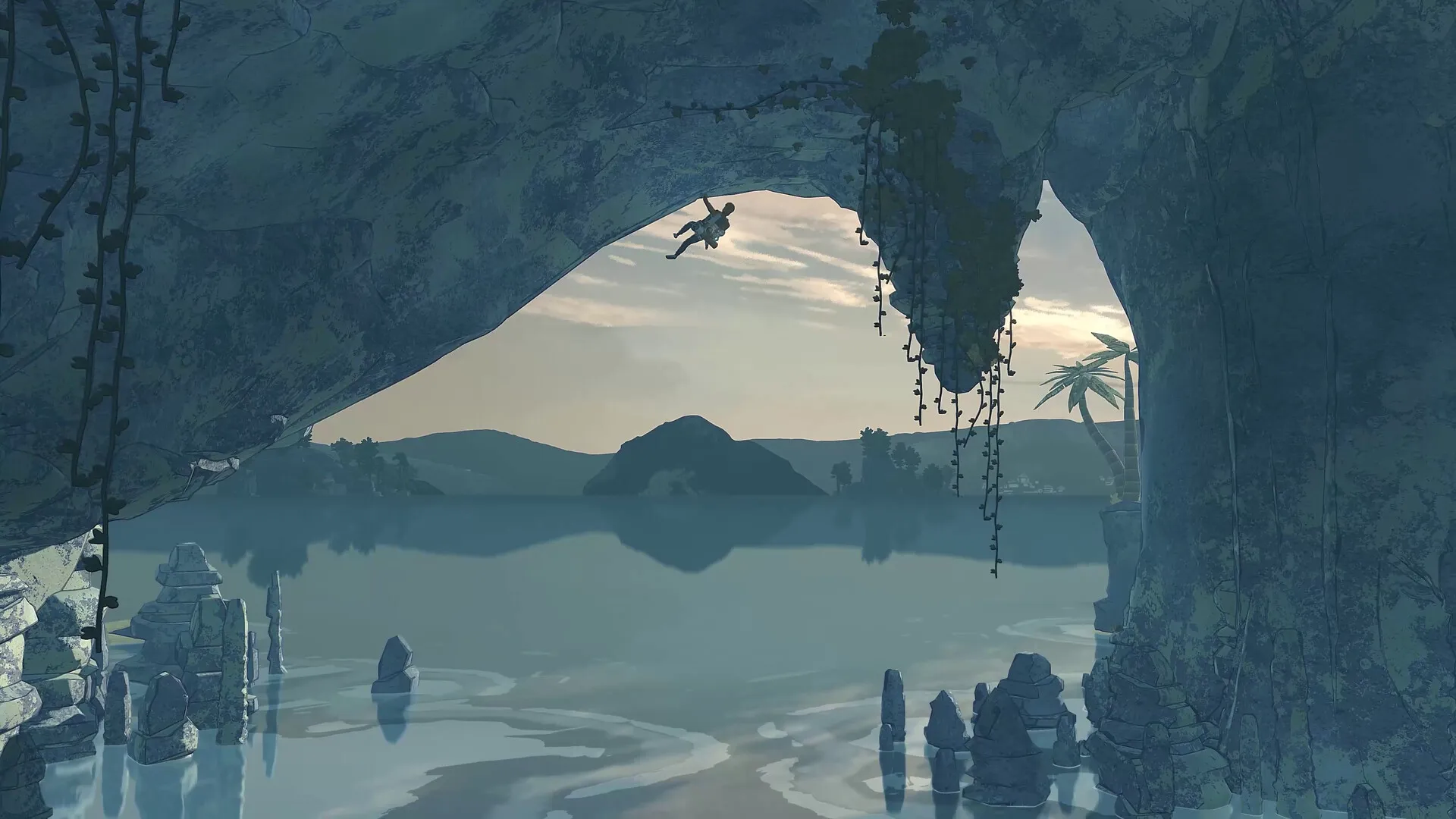A Cairn climber hangs from a cave roof above a calm lagoon dotted with stone stacks