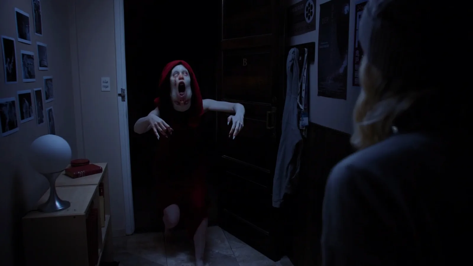 A creature in a red dress, mouth gaping, lunges at a blonde woman in a Tenebris Somnia hallway